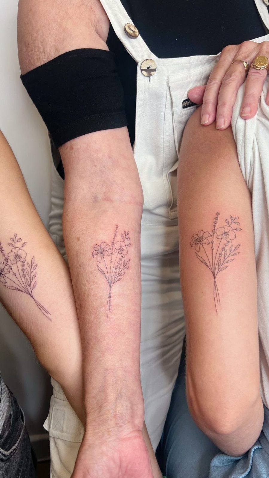 Trois bouquets de fleurs identiques en fine line sur trois avant-bras